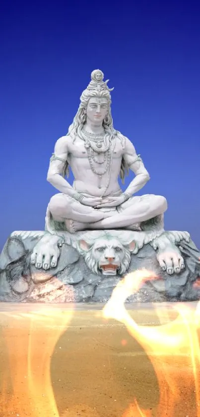 Majestic Shiva statue against a vibrant blue sky in a serene desert landscape.