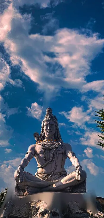 Shiva statue under majestic blue sky with clouds.