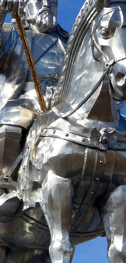 Metallic statue of a rider on horseback against a blue sky.