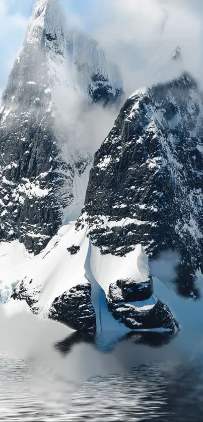 Snowy mountains with reflective water and misty clouds.