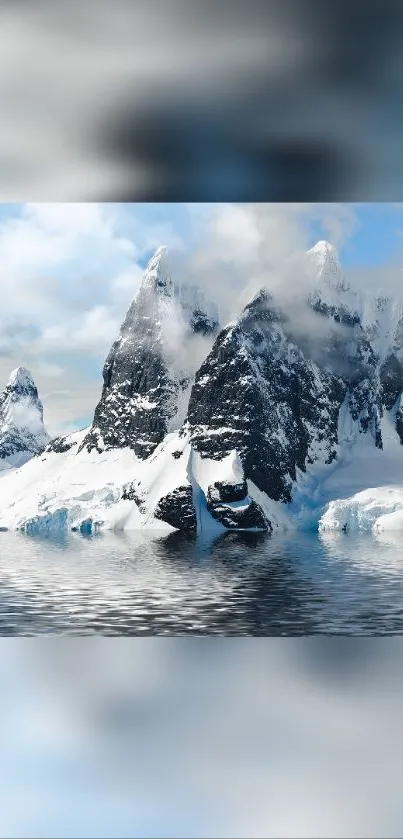 Snowy mountain peaks reflecting on calm water under a blue sky.