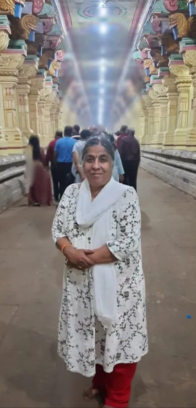 A woman stands in a vibrant temple corridor with yellow columns and intricate designs.