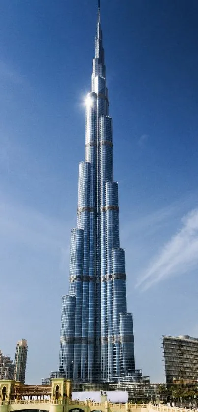 Majestic skyscraper under a clear blue sky with urban skyline in view.