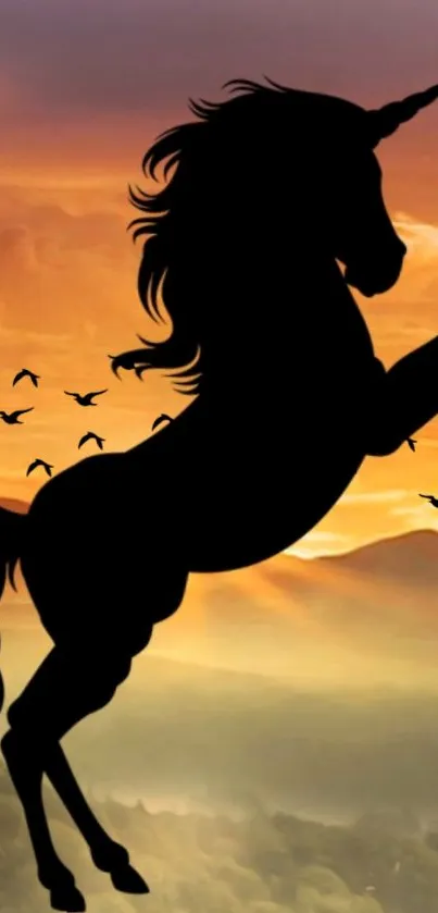 Silhouette of a unicorn against an orange sunset sky with birds in flight.