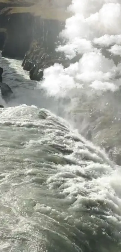 Majestic waterfall with misty clouds cascading down rocky cliffs.