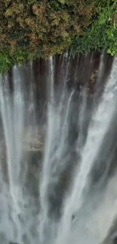 Majestic waterfall cascading down through lush green landscape.