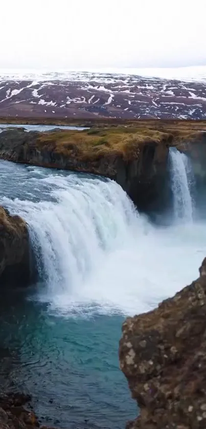 Breathtaking waterfall amidst snowy cliffs.