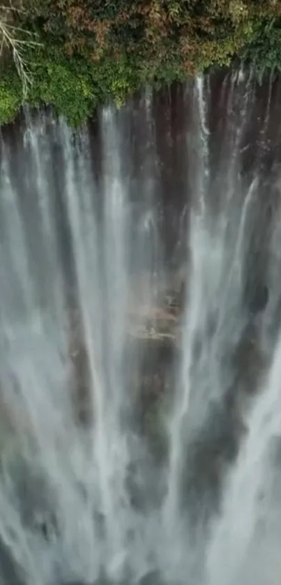 Aerial view of a majestic waterfall cascading over lush green cliffs.