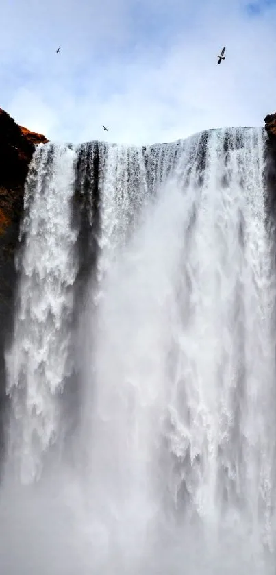 Majestic waterfall with a red-clothed figure and birds against cliffs.