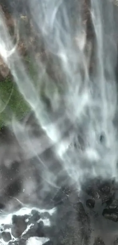 A beautiful waterfall cascades over rocks with lush green surroundings.