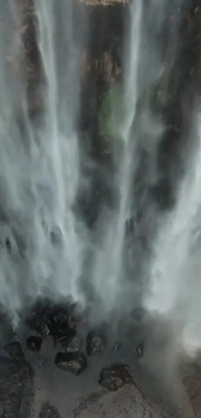 Majestic waterfall with mist cascading down rocks in serene landscape.