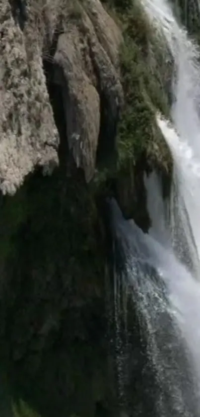 Majestic waterfall cascades down cliffs with lush greenery beneath.