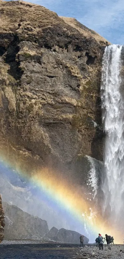 Majestic waterfall with rainbow under clear sky.