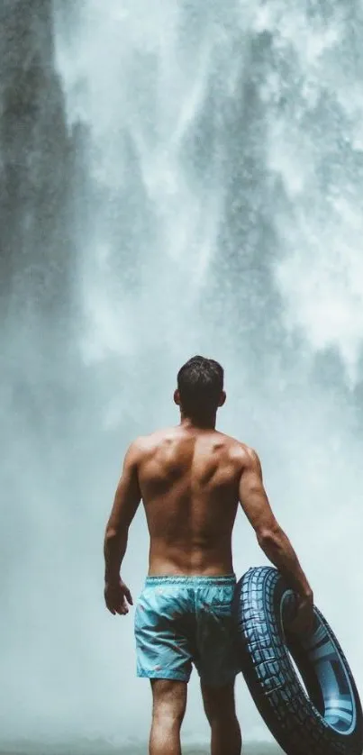 Man with tire facing a powerful waterfall.