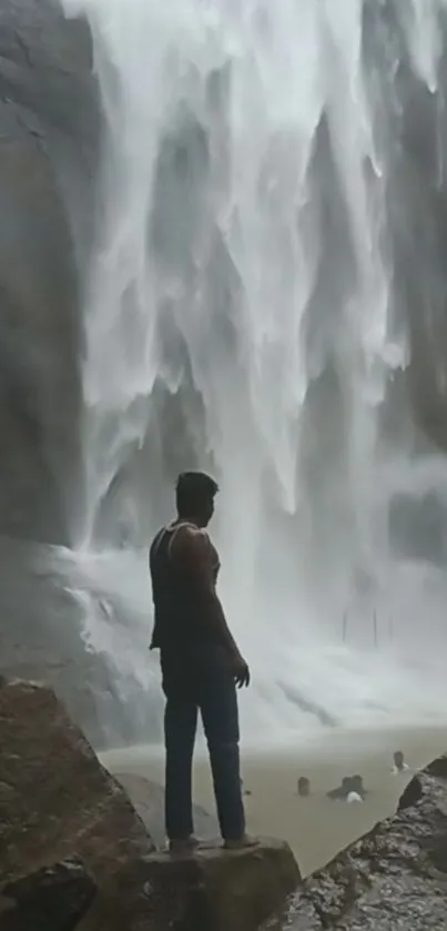 Person standing near majestic waterfall.