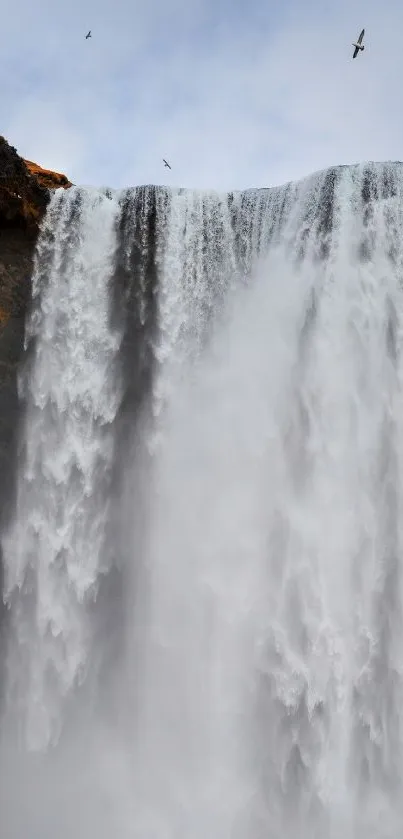 Majestic waterfall cascading down rugged cliffs in a stunning nature scene.