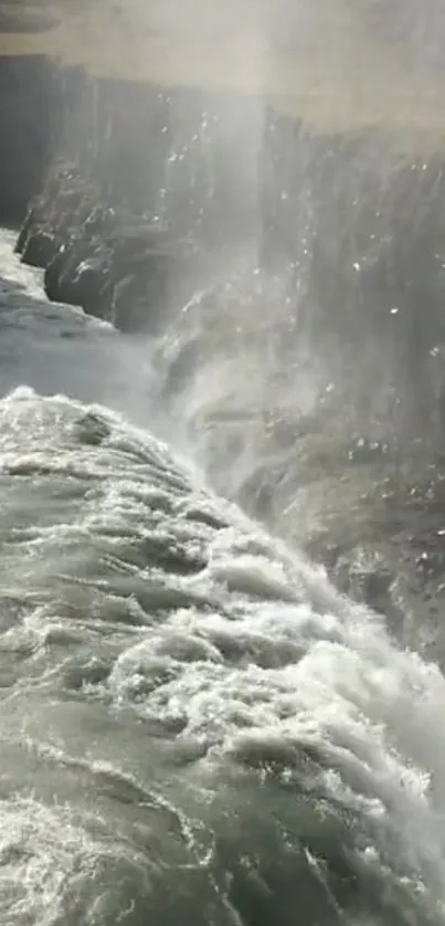 Stunning waterfall cascading down cliffs with mist rising in a serene setting.