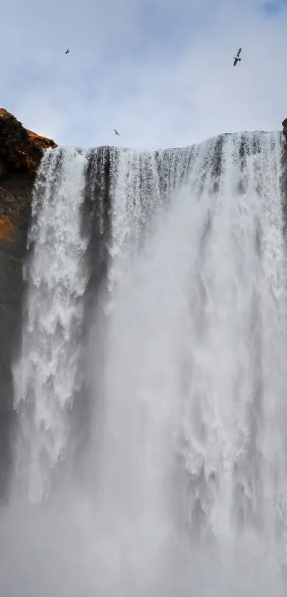 Breathtaking waterfall with mist and a tiny figure gazing up in awe.