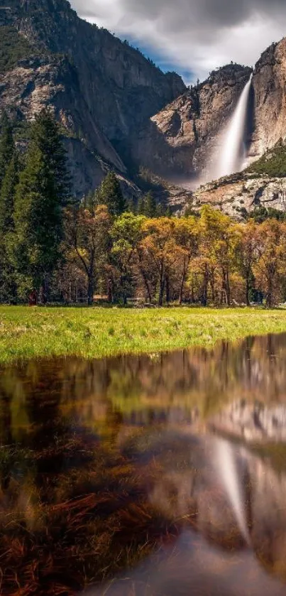 Majestic waterfall above colorful autumn forest reflected in tranquil water.