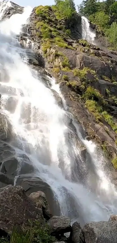 Majestic waterfall cascading down rocky cliffs with lush green surroundings.