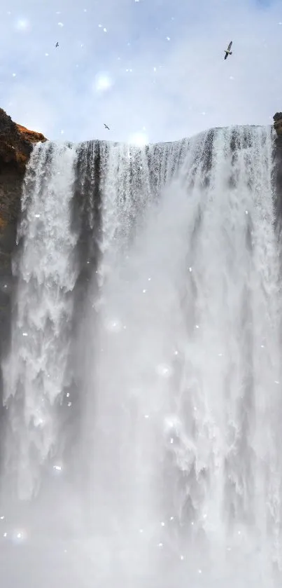 Majestic waterfall cascading down rocky cliffs with mist and serene skies.