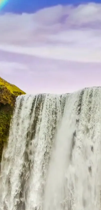 Waterfall with rainbow under a blue sky.