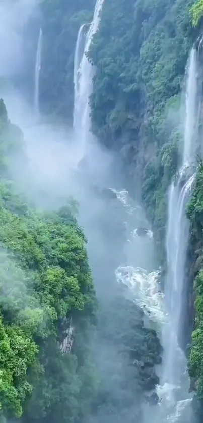 Majestic waterfalls cascading through lush greenery enveloped in mist.