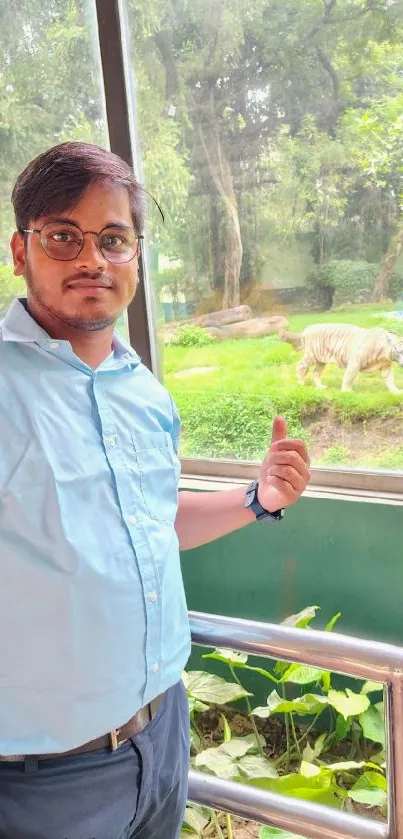 Man standing by glass, white tiger in background.