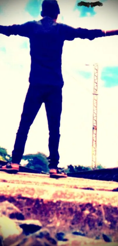 Man standing on railway track with open arms under blue sky.