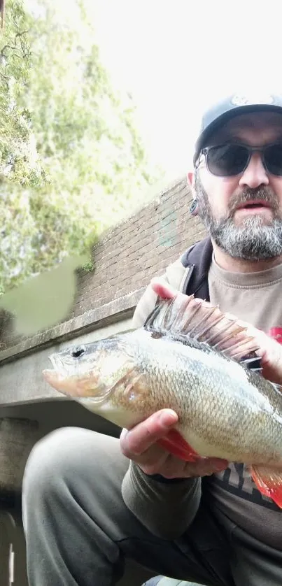 Man holding a large freshwater fish outdoors.