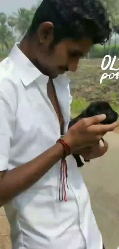 A man gently holds a small puppy outdoors.