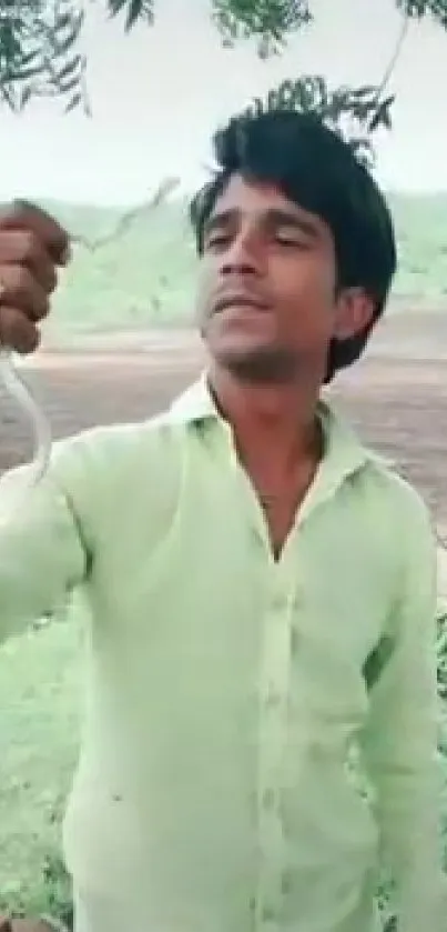 Man in green shirt holding a small snake.