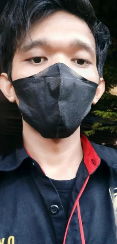 Person wearing a black mask and shirt in an urban setting.