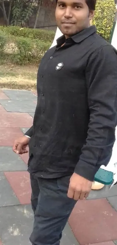 Man in black shirt standing in a park playground setting.