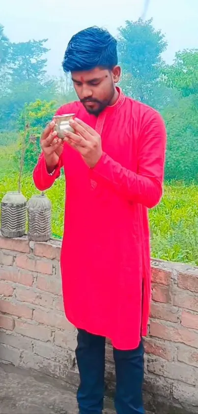 Man in red kurta enjoys nature's backdrop.