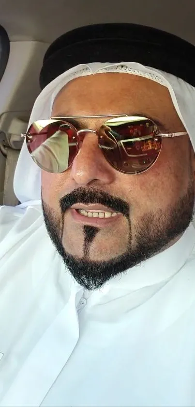 Man in traditional attire and sunglasses in car.