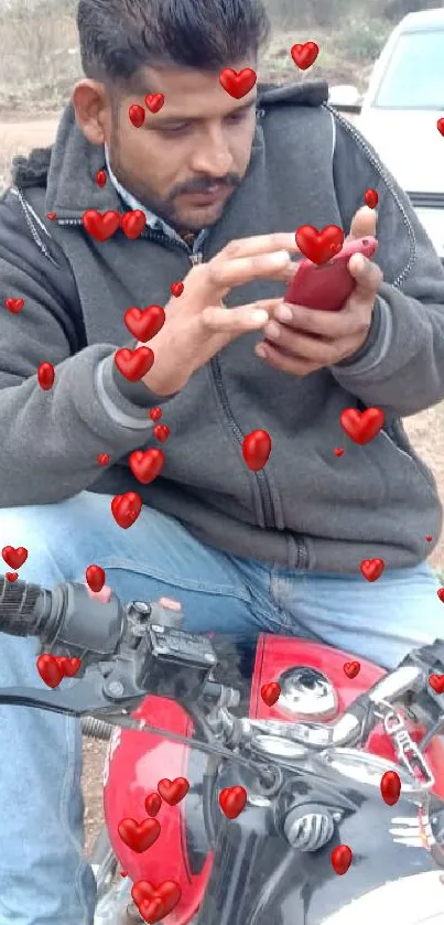 Man looking at smartphone while sitting on a red motorcycle.