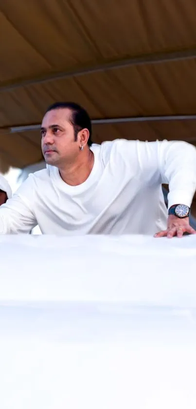 Man holding smartphone on boat with tented roof.