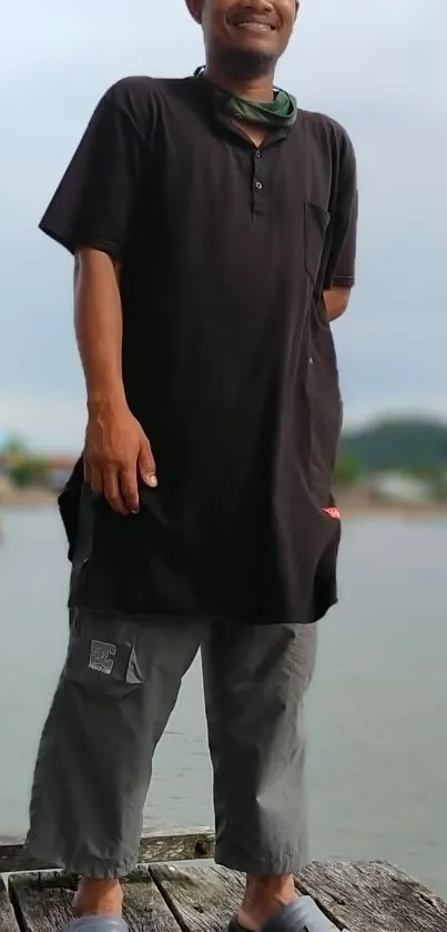 Man standing on a dock by the lake with a serene backdrop.