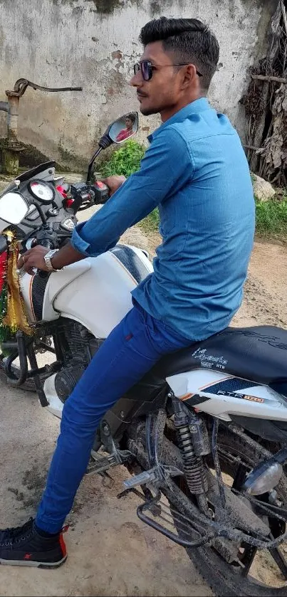 Man on a motorcycle in a rural setting, wearing a blue shirt.