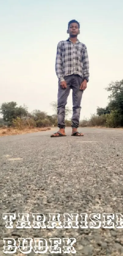 A person stands on an open road, surrounded by nature.