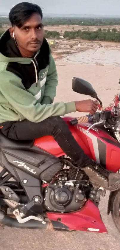 Man sitting on a red motorcycle with a landscape view.