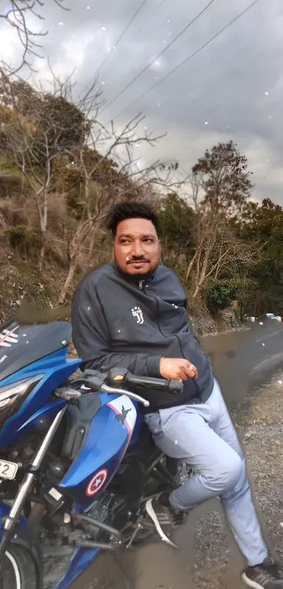 Man leans on blue motorcycle on a scenic rural road.