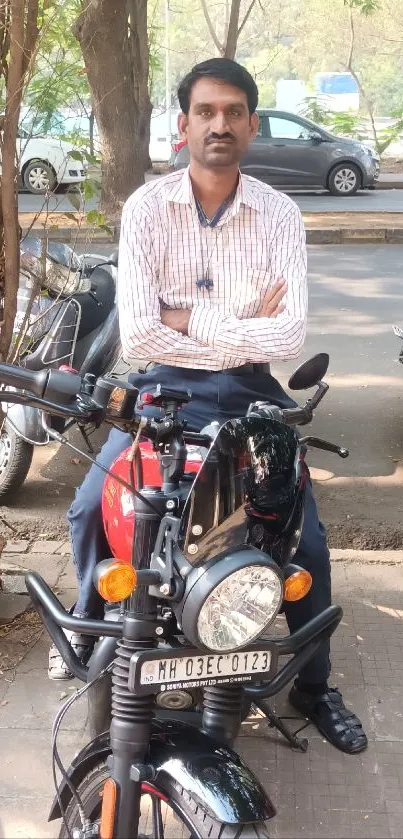 Man on a parked red motorcycle on an urban street.