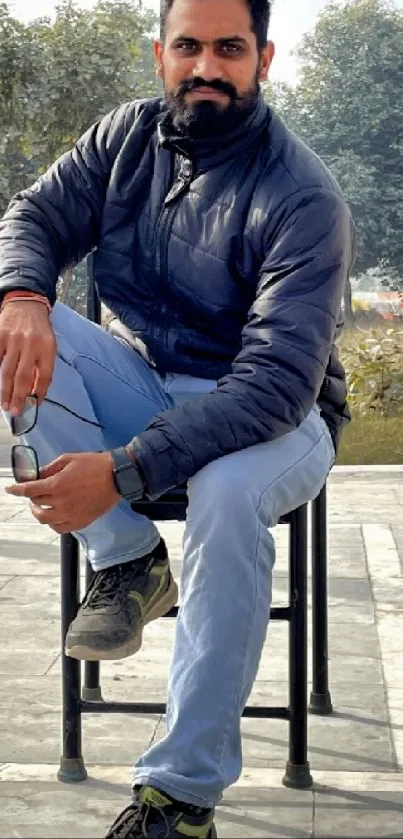 Man sitting in a park with winter attire, stylish and serene vibe.