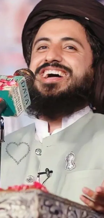 Smiling man in traditional attire speaking at a public event.