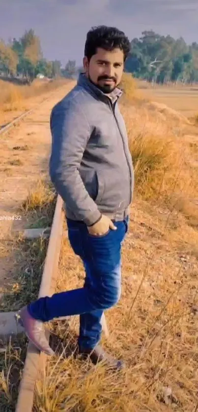 Man standing on railway track surrounded by golden grass.