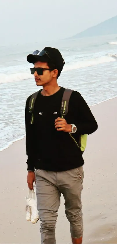 Man walking on a beach with ocean waves in the background.