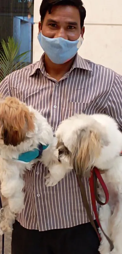 Man wearing a mask holding two dogs indoors.