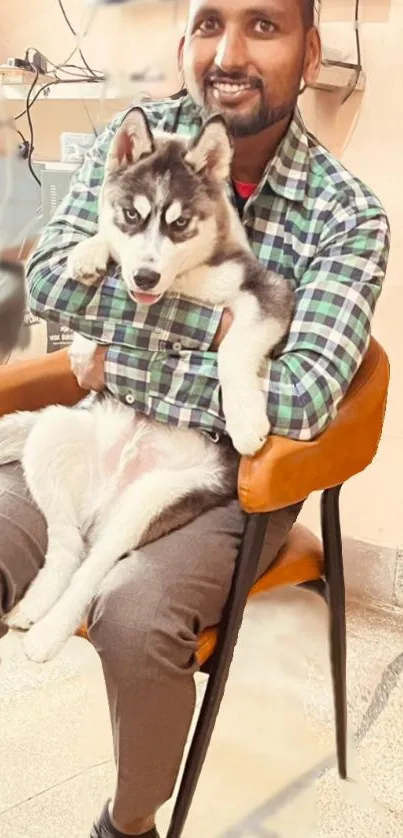 Man sitting with husky puppy on chair in cozy setting.